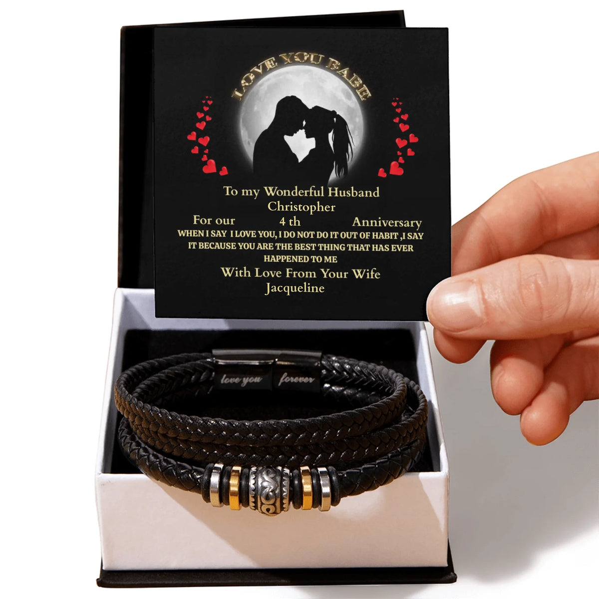 Black leather bracelet with engraved message in a box held by a hand