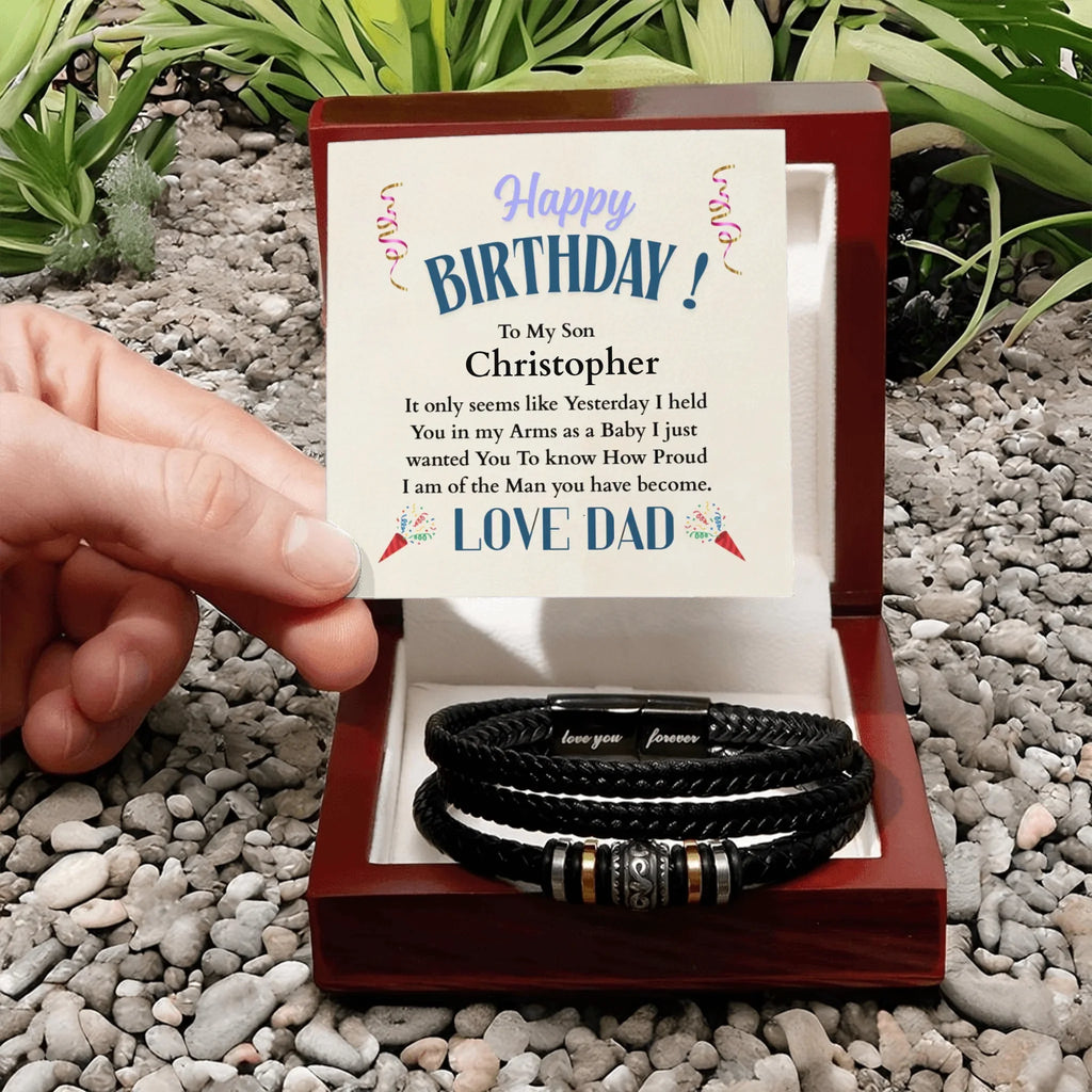 Gift box with leather bracelets and birthday card on pebbles with plants