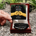 Personalized bracelet set in a decorative box with a Christmas card on a pebbled surface.