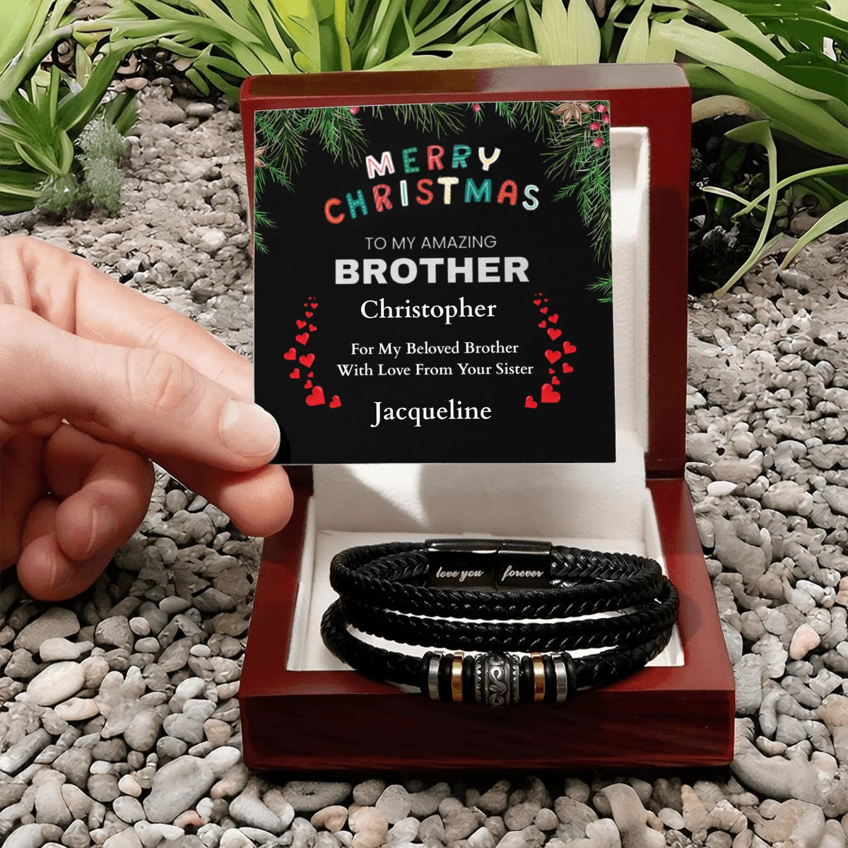 Personalized Christmas card with bracelets in a box on a pebble and plant background