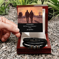 Hand holding a box with leather bracelets and a Valentine's Day card on pebbles with plants.