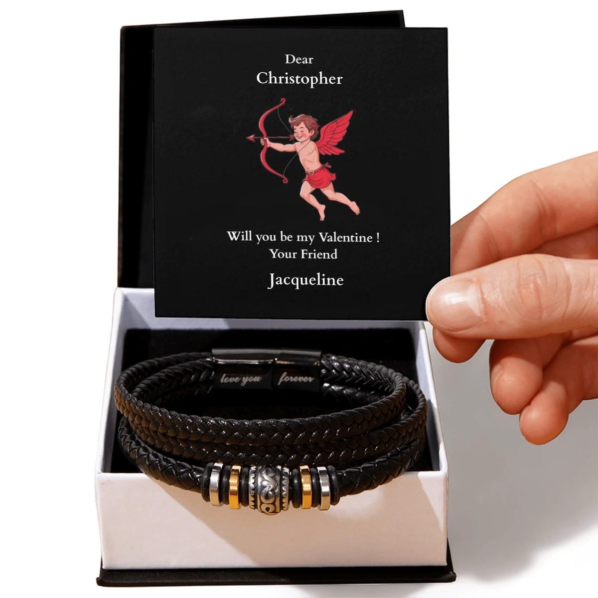 Black leather bracelet with metal charms in a box, held by a hand, with a sentimental message card.