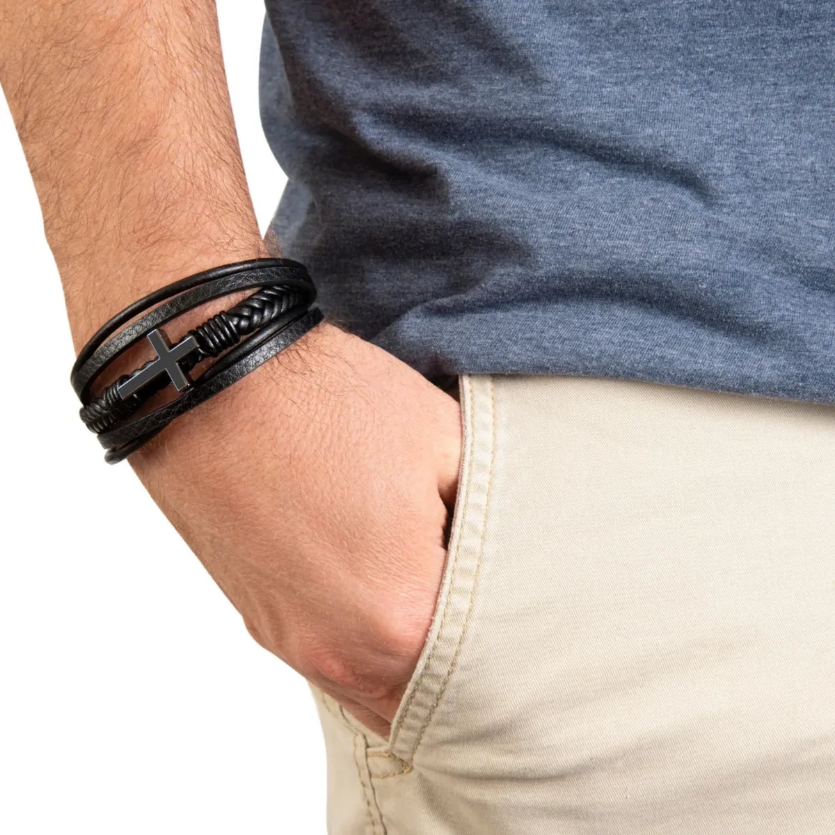 Close-up of a person's wrist wearing multiple black leather bracelets on a neutral background