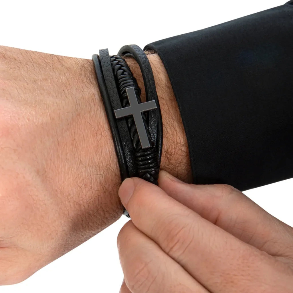 Black leather bracelet with a cross charm on a wrist against a white backgroundbackground