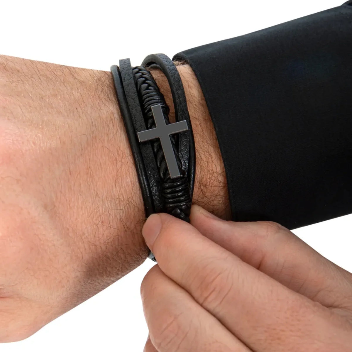 Black leather bracelet with a cross charm on a wrist against a white background